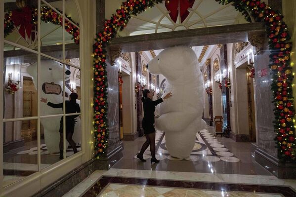 Сотрудник отеля помогает аниматору в костюме белого медведя после развлечения гостей накануне Рождества в Пекине, Китай  - Sputnik Латвия