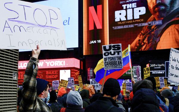 Участники митинга в Нью-Йорке против военной операции США в Венесуэле. Один из них держит в руках плакат с надписью: "Остановите американский империализм" - Sputnik Латвия