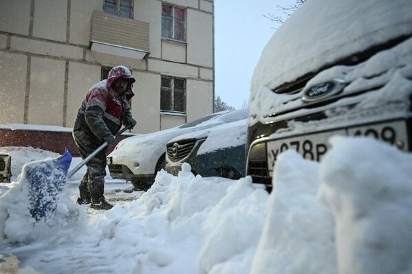Сотрудник коммунальных служб убирает снег на улице в Москве, Россия - Sputnik Латвия