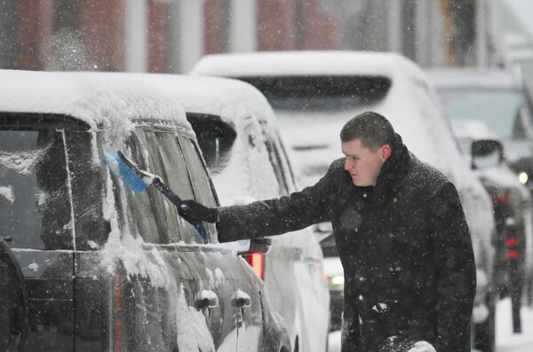 Мужчина расчищает машину от снега - Sputnik Латвия