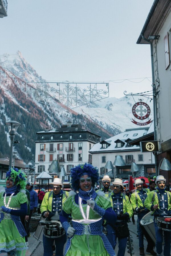 Танцоры и музыканты проходят парадом по заснеженным улицам Шамони во Франции. - Sputnik Латвия