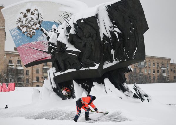 Сотрудник коммунальной службы убирает снег у памятника Героям Первой мировой войны на территории парка Победы - Sputnik Латвия