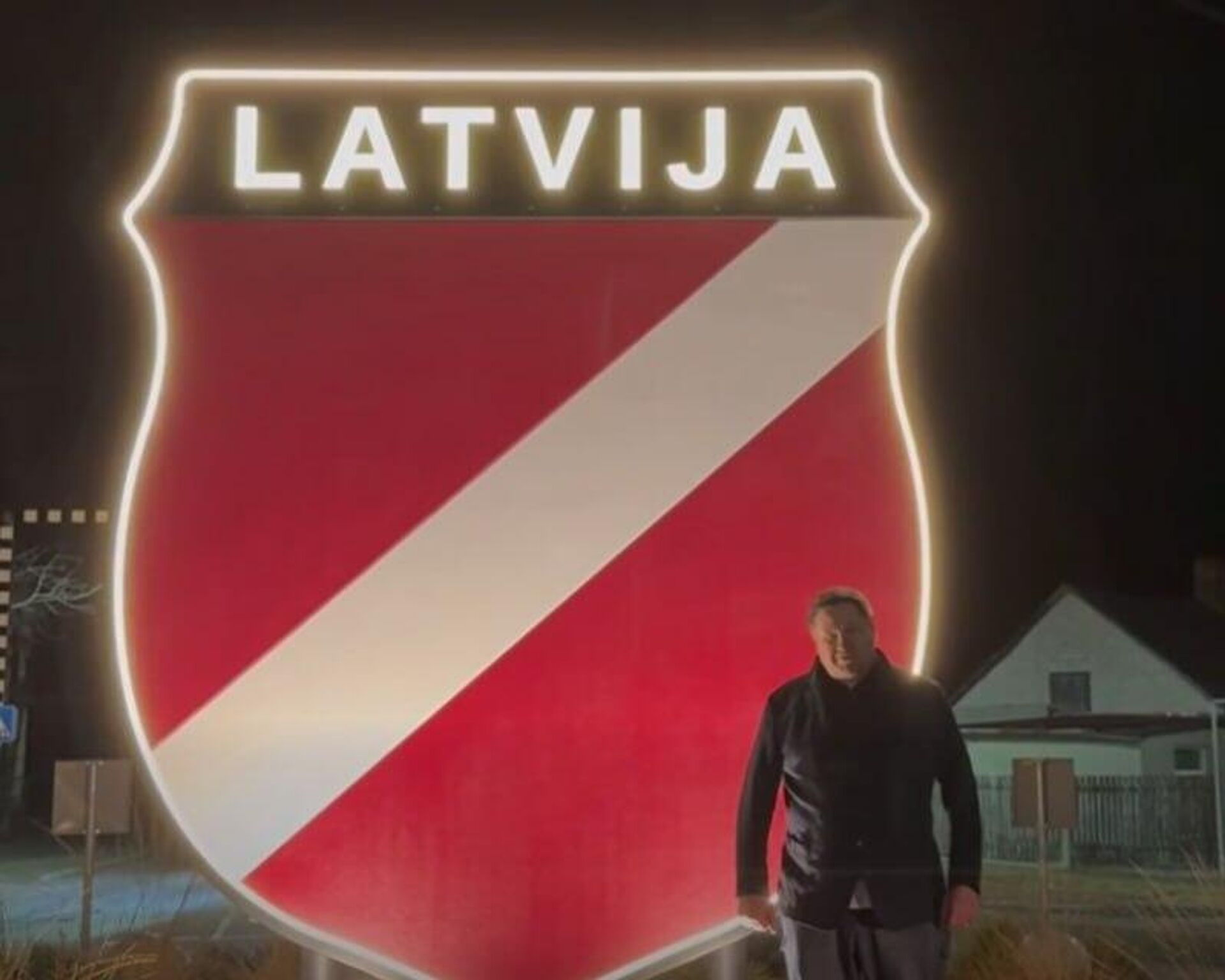 Бывший мэр Огре Эгилс Хелманис записывает обращение на фоне эмблемы латышского легиона СС - Sputnik Латвия, 1920, 16.03.2026