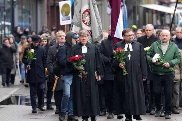 Люди идут по центру Риги с флагами, цветами, плакатами и эмблемами латышского легиона СС. - Sputnik Латвия