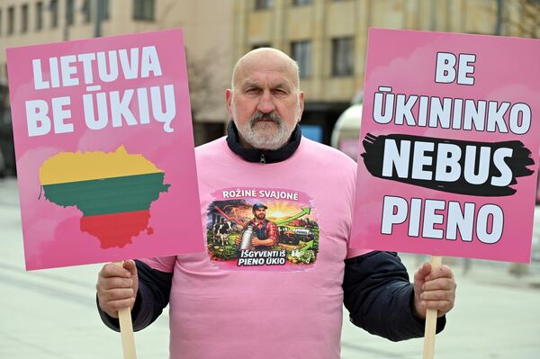 На фото: участник акции протеста держит плакаты с надписями: "Литва без сельского хозяйства", "Без фермера не будет молока". - Sputnik Латвия