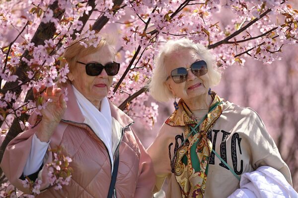 В воздухе витает романтичная атмосфера — люди фотографируются на фоне нежных лепестков и просто любуются чудом пробуждения природы. - Sputnik Латвия
