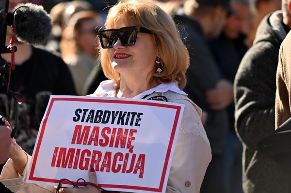 На фото: участница акции протеста держит плакат с надписью: "Остановите массовую иммиграцию". - Sputnik Латвия