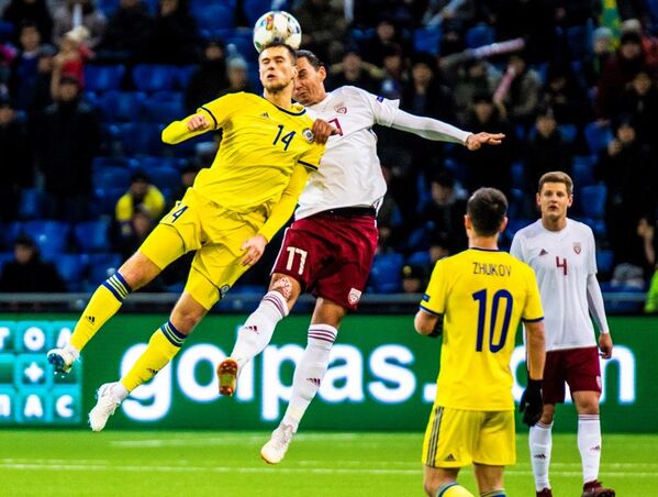 Роман Муртазаев (слева) бьется за мяч с игроком сборной Латвии в матче Лиги наций, Астана, 15 ноября 2018 года - Sputnik Латвия