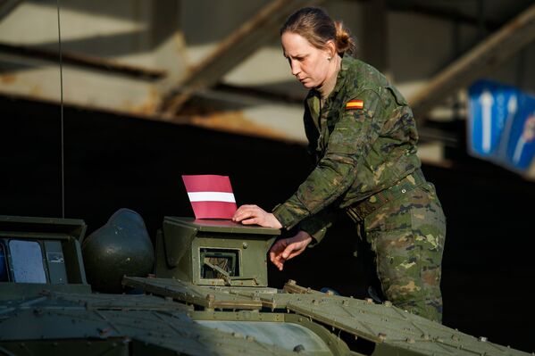 Военнослужащая Испании прикрепляет латвийский флажок к бронетехнике - Sputnik Латвия