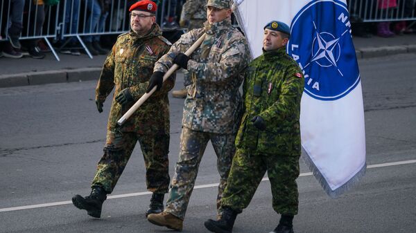 Немецкий, латвийский и канадский военные с флагом Расширенной передовой группы НАТО в Латвии - Sputnik Latvija