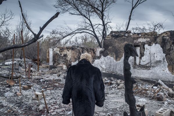 Женщина у разрушенного дома в поселке Саханка Донецкой области - Sputnik Латвия