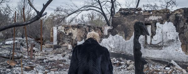 Женщина у разрушенного дома в поселке Саханка Донецкой области Женщина у разрушенного дома в поселке Саханка Донецкой области - Sputnik Latvija