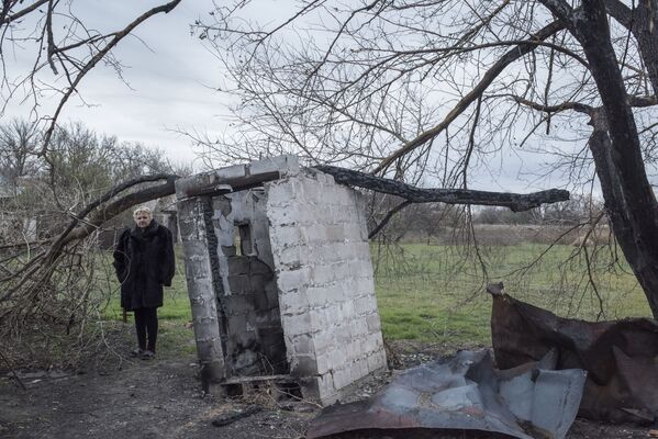 Женщина у разрушенного дома в поселке Саханка Донецкой области - Sputnik Латвия