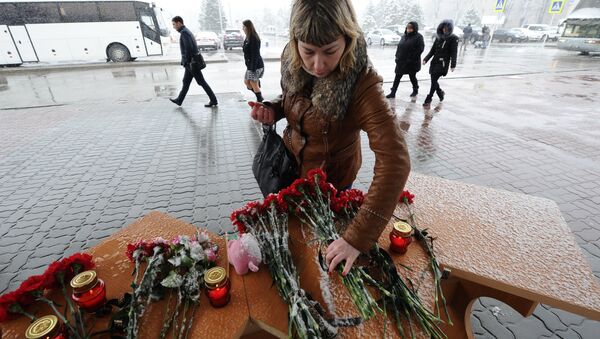 Женщина возлагает цветы у аэропорта Ростова-на-Дону - Sputnik Латвия