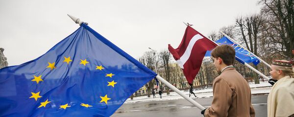 Юноша и девушка в национальных латышских костюмах с флагами ЕС и Латвии у Памятника Свободы в Риге - Sputnik Latvija