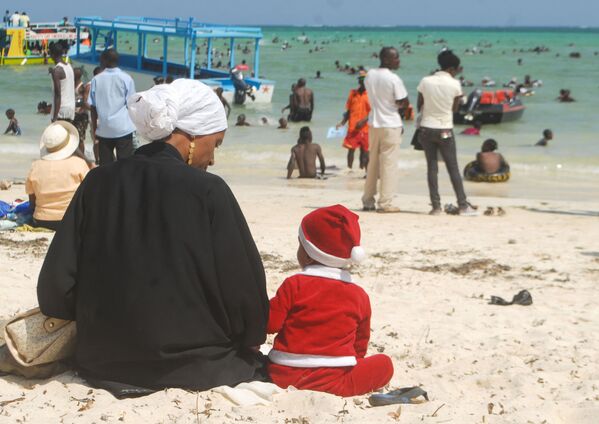 Мальчик в костюме Санта-Клауса рядом с матерью на пляже в Кении  - Sputnik Латвия
