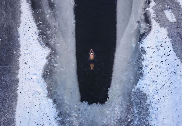 Человек плавает в частично замерзшем озере в Шэньяне, провинция Ляонин - Sputnik Латвия