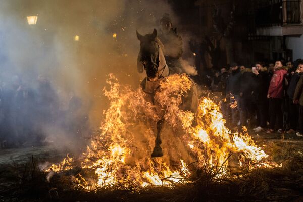 Всадник проезжает через огонь во время ежегодного фестиваля Las Luminarias в испанской деревне Сан-Бартоломе-де-Пинарес - Sputnik Латвия