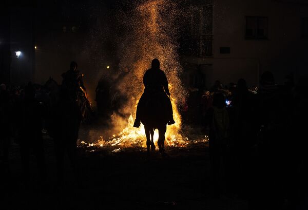 Всадник проходит через огонь во время ежегодного фестиваля Las Luminarias в испанской деревне Сан-Бартоломе-де-Пинарес - Sputnik Латвия