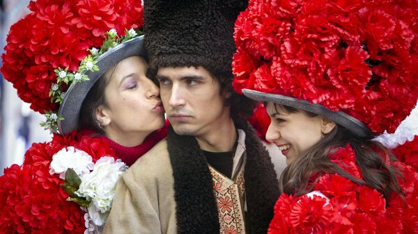 Юноша в традиционном румынском костюме в окружении девушек в цветочных нарядах в Бухаресте - Sputnik Латвия