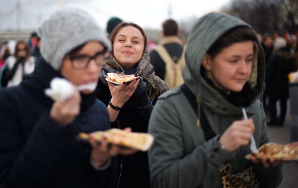 Девушки едят блины во время масленичных гуляний в Парке Горького в Москве - Sputnik Латвия