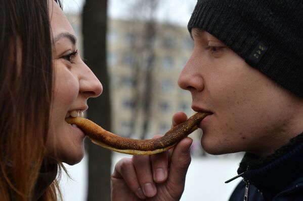 Молодые люди едят блин на празднике Широкая Масленица в Казани - Sputnik Латвия