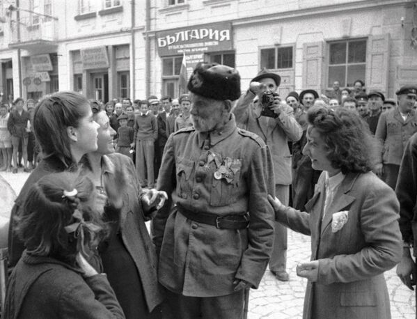 Ветеран турецкой войны беседует с девушками, в освобожденном войсками РККА от фашистов, болгарском городе, 1944 год - Sputnik Латвия