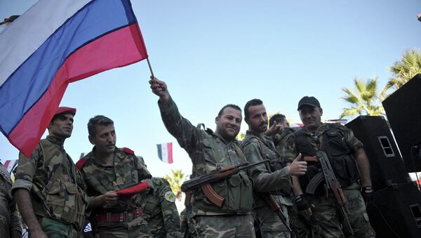 Сирийские военные с российским флагом во время митинга в городе Тартус, Сирия - Sputnik Latvija