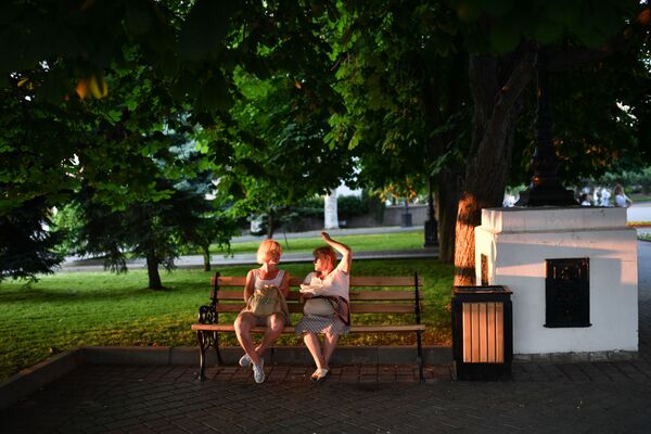 Отдыхающие сидят на скамейке в парке в Севастополе в Крыму - Sputnik Латвия
