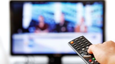 Мужчина держит пульт перед телевизором, архивное фото