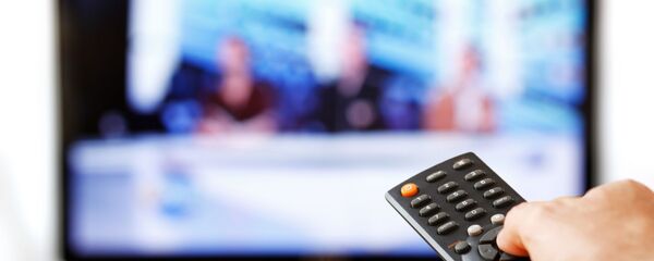 Мужчина держит пульт перед телевизором, архивное фото - Sputnik Латвия