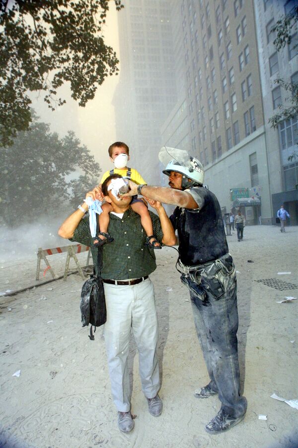 Полицейский помогает при эвакуации людей из Всемирного торгового центра 11 сентября 2001 года - Sputnik Латвия