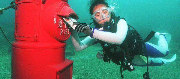 Водолаз кладет пластиковое письмо в почтовый ящик, установленный на глубине 10 метров на дне моря у берегов Сузами в префектуре Вакаяма - Sputnik Латвия