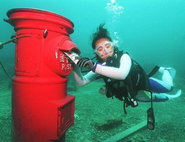 Водолаз кладет пластиковое письмо в почтовый ящик, установленный на глубине 10 метров на дне моря у берегов Сузами в префектуре Вакаяма - Sputnik Латвия
