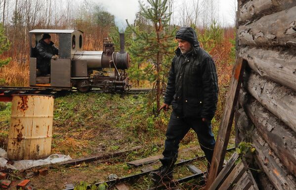 Инженер-энтузиаст Павел Чилин проходит мимо своего самодельного паровоза, который проезжает по железной дороге в поселке Ульяновка Ленинградской области - Sputnik Латвия