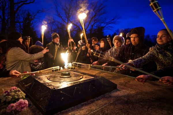Рижане зажигают факелы от Вечного огня на Братском кладбище в Риге в День Лачплесиса - Sputnik Латвия