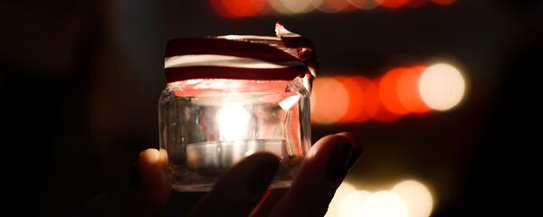 Рижане зажигают поминальные свечи у стены Рижского замка в День Лачплесиса - Sputnik Латвия