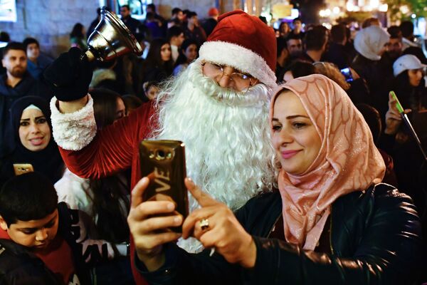 Sieviete fotografējas ar vīrieti Santa Klausa tērpā Ziemassvētku svinībās Sīrija Latakijā. - Sputnik Latvija
