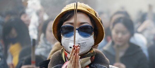 Женщина в маске и солнцезащитных очках во время молитвы в первый день Нового года в Пекине - Sputnik Latvija