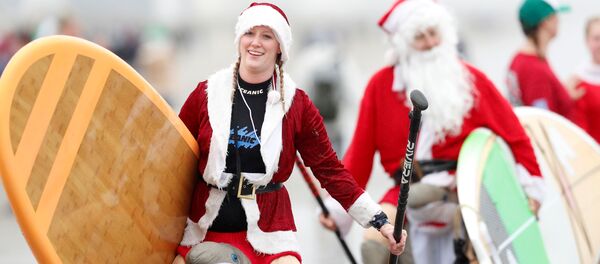 Участники ежегодного заплыва серферов в костюмах Санта-Клауса в США  Участники ежегодного заплыва серферов в костюмах Санта-Клауса в США  - Sputnik Latvija