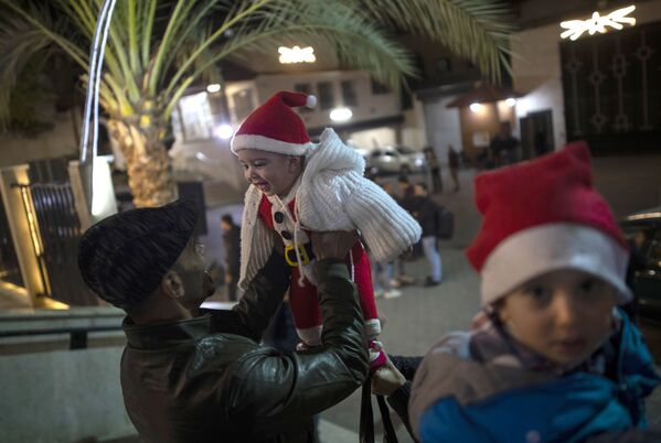 Мужчина играет с ребенком до начала рождественской мессы в Газе. - Sputnik Латвия
