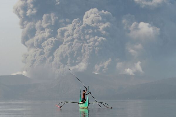 Молодой рыбак на каноэ у подножия вулкана Таал, извергающего пепел, к югу от Манилы - Sputnik Латвия