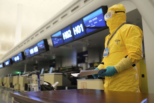 Работник в защитном костюме в аэропорту Уханя, Китай - Sputnik Латвия