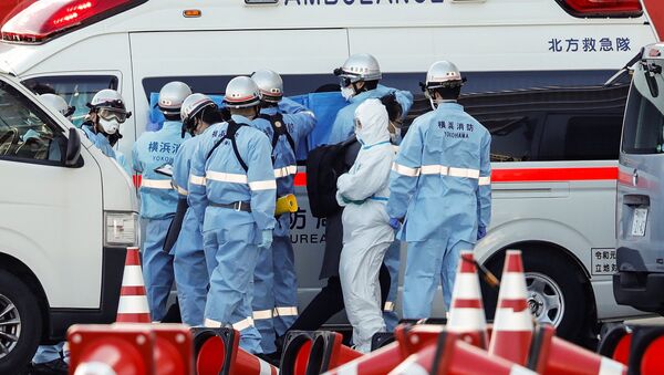 Пожарные в защитных костюмах помещают в машину скорой помощи заболевших пассажиров круизного лайнера Diamond Princes, помещенного в карантин у японского порта Йокогама - Sputnik Latvija