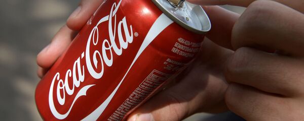 Покупатель держит банку с напитком компании Coca-Cola - Sputnik Латвия