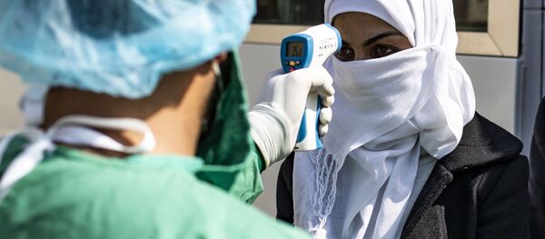 Медик проверяет температуру тела пассажирки, в качестве превентивной меры против коронавируса - Sputnik Латвия