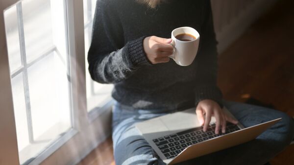 Женщина пьет кофе во время работы за ноутбуком - Sputnik Латвия