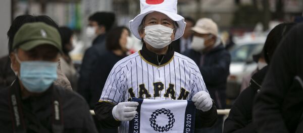 Мужчина держит в руках полотенце с логотипом Олимпийских игр в Токио 2020 Мужчина держит в руках полотенце с логотипом Олимпийских игр в Токио 2020 - Sputnik Latvija