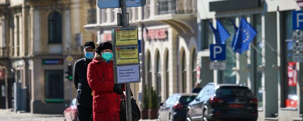 Женщина и мужчина в защитных масках на остановке общественного транспорта в Риге Женщина и мужчина в защитных масках на остановке общественного транспорта в Риге - Sputnik Latvija