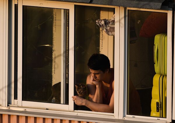Молодой человек с кошкой на балконе многоквартирного дома в Москве - Sputnik Латвия
